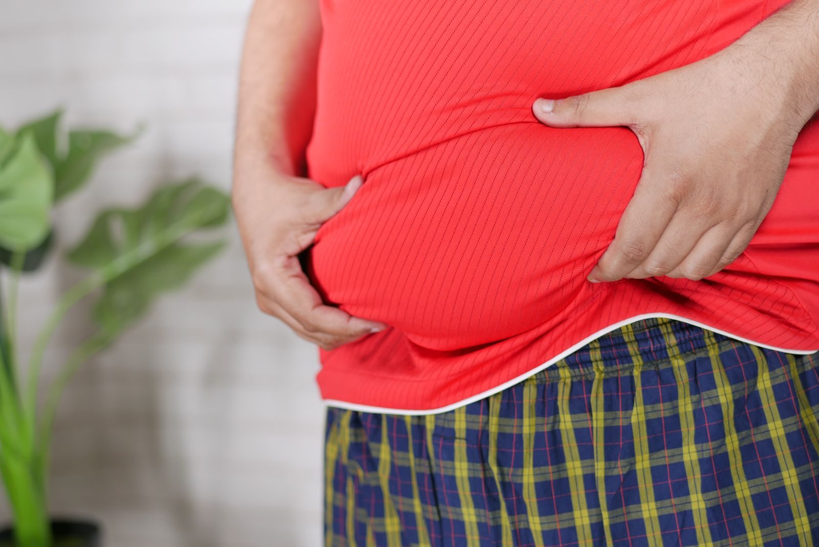 Homem segurando a barriga: obesidade e ereção